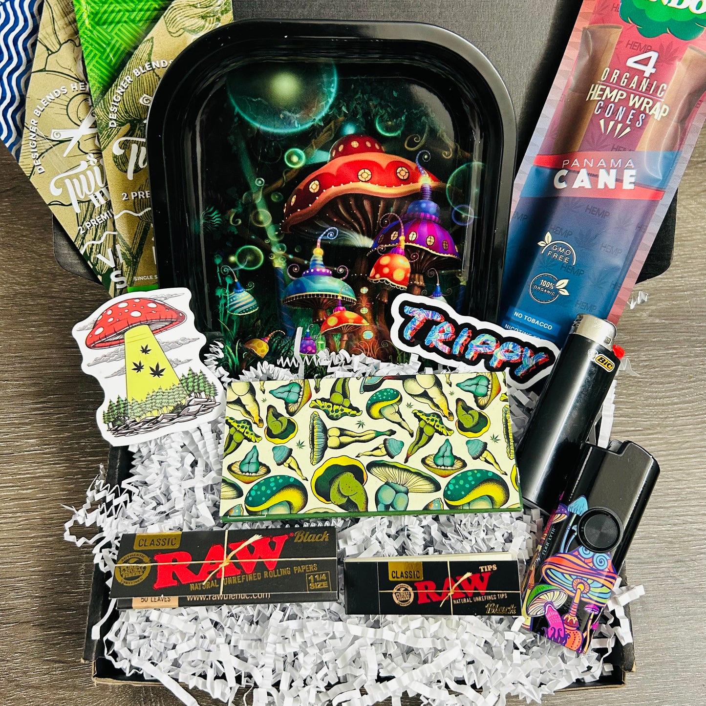Shroom'd out box includes a mushroom rolling tray, hemp wraps, lighter, rolling papers, tips, flkr lytr spinner, hemp cones, and stickers in black gift box with shredded paper.
